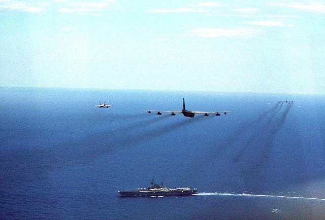 F/A-18 Hornet aircraft from the aircraft carrier USS MIDWAY (CV 41) fly fly alongside two Air Force B-52G Stratofortress aircraf