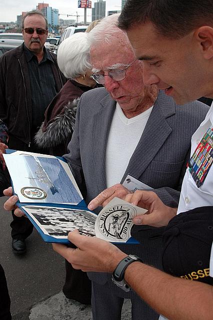 (June 2, 2007) - Retired Chief Signalman William Schwarz shows USS Russell (DDG 59) commanding officer, Cmdr. Brad Cooper a phot