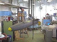 Bob Solomon (LCDR AO Ret.) painting the AME Shop (Space C-150) on the ship, with MK-82 Mod 1(inert) on hoist making ready for di